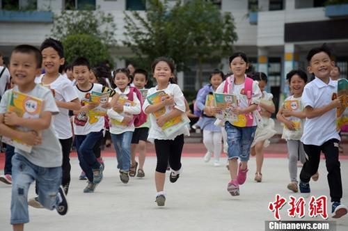 资料图：一年级的新同学怀抱新书本开心的走出教室，奔跑在校园里。<a target='_blank'  data-cke-saved-href='http://www.chinanews.com/' href='http://www.chinanews.com/'>中新社</a>记者 张娅子 摄